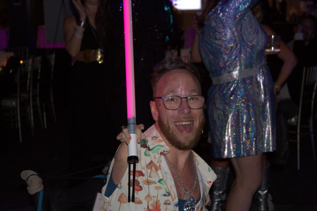 TJ smiling with a light saber