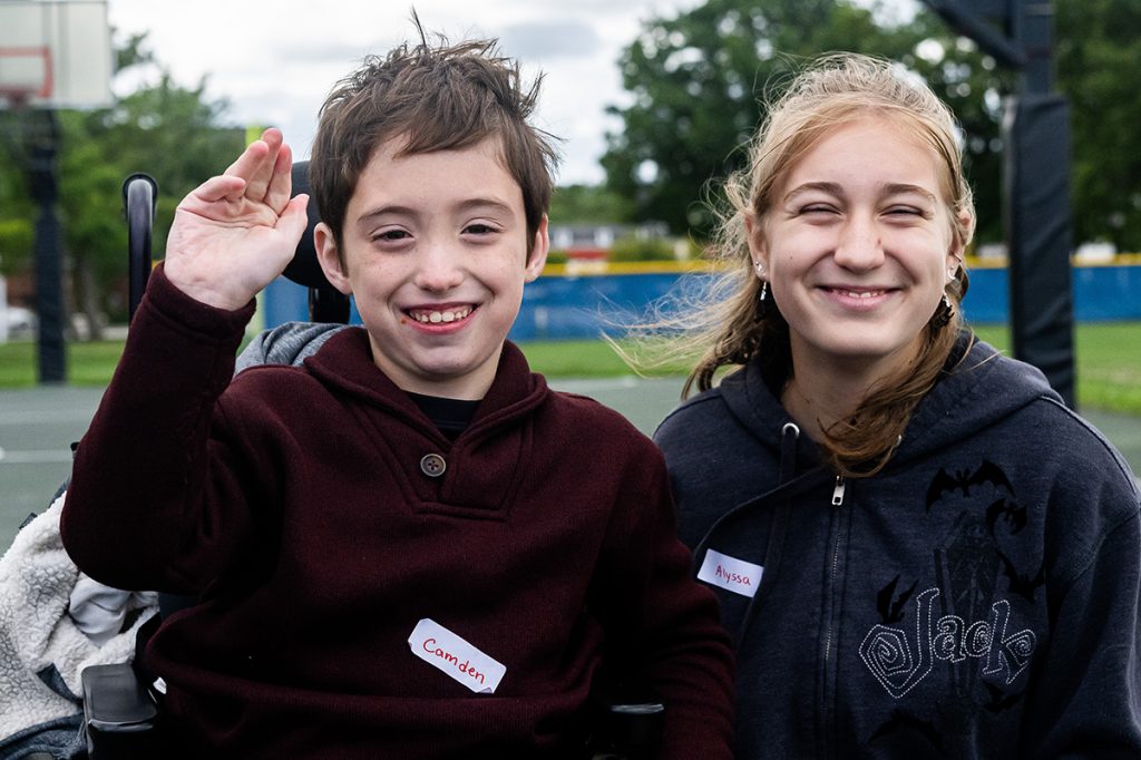 A participant and volunteer smile and wave, looking happy.