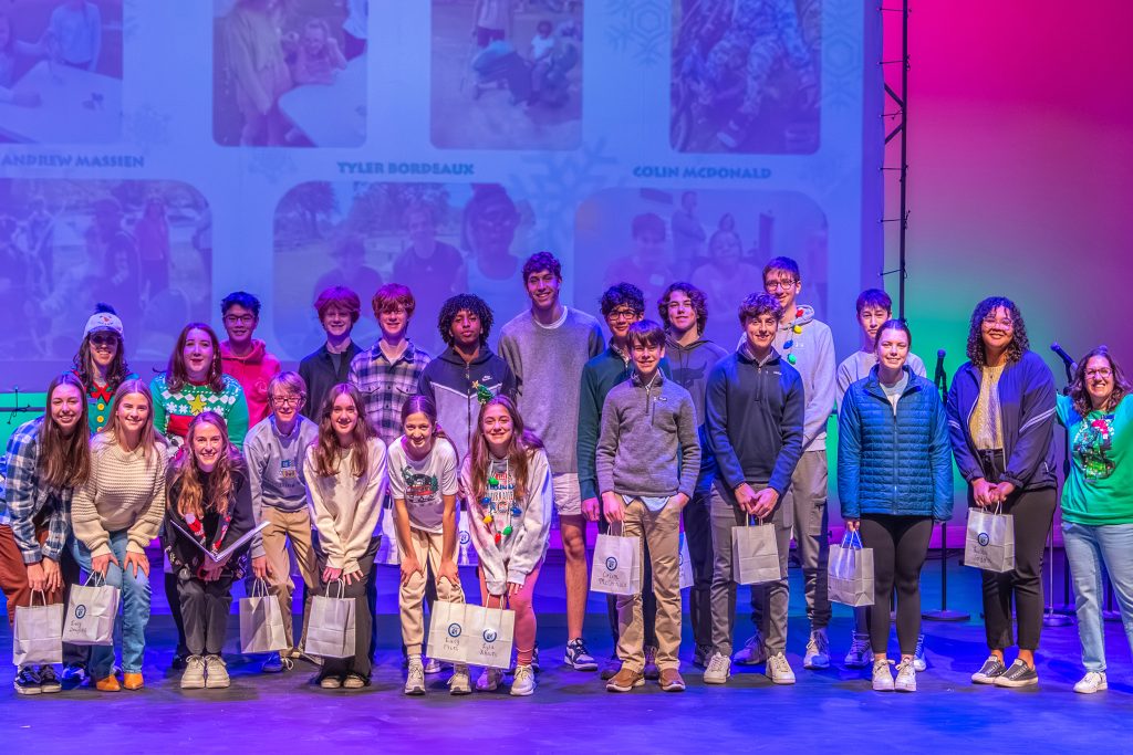 A group of kids on a stage with vibrant colored lighting