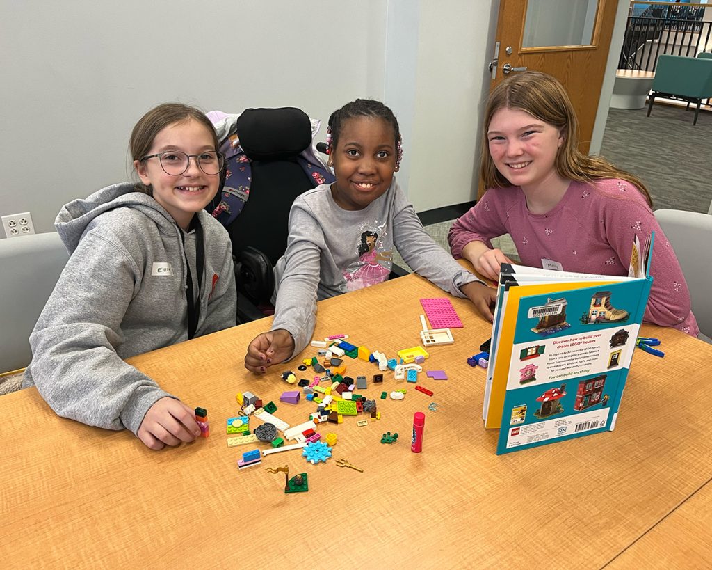 A group of girls sitting at a table playing legos