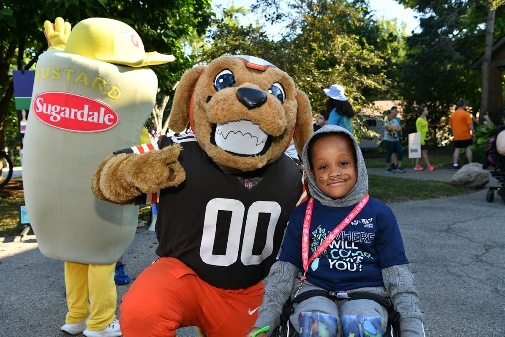 Boy sitting next to Chomps the Browns mascot