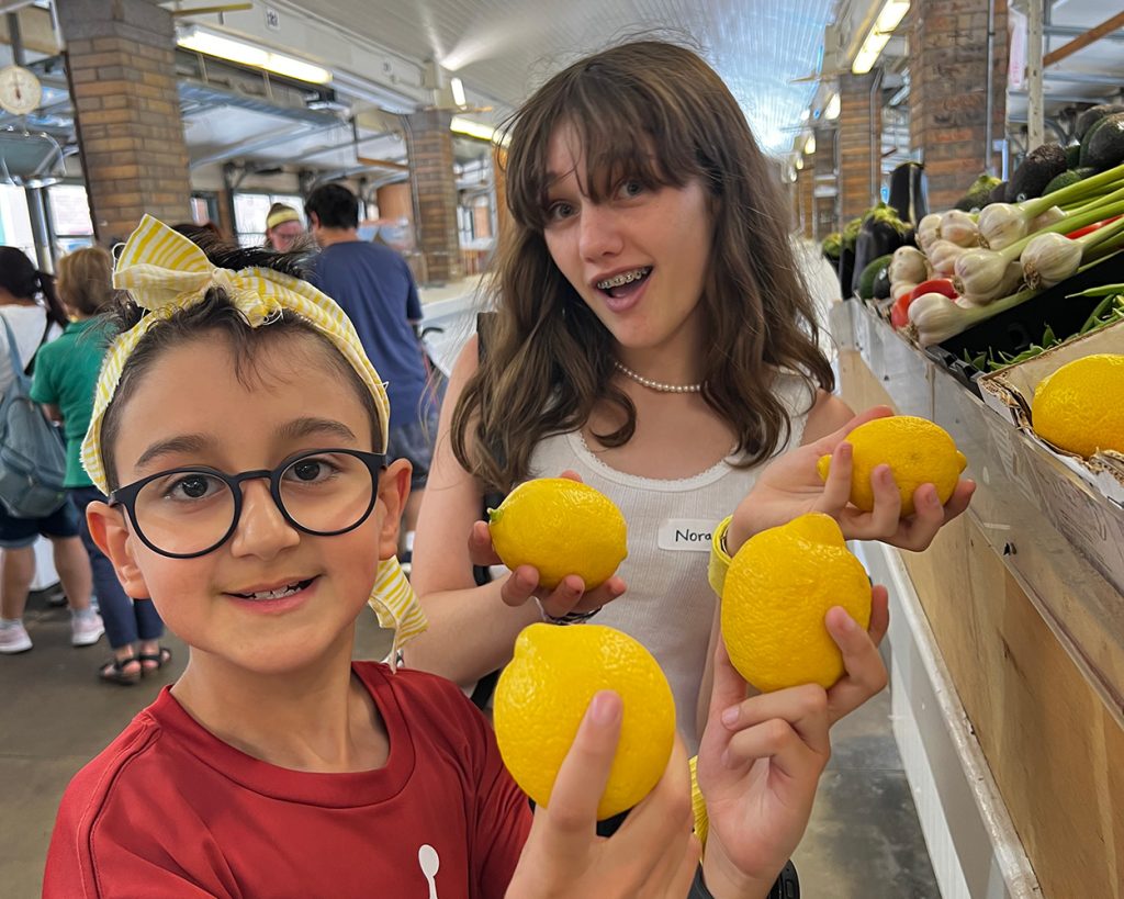 Two Children holding citrus in a market