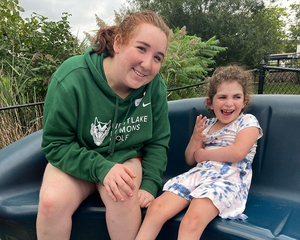 A teenager leaning over with a child in a white dress