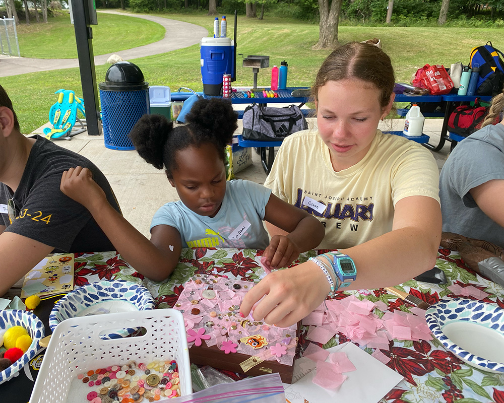 A teenager and a girl sitting at a table, crafting
