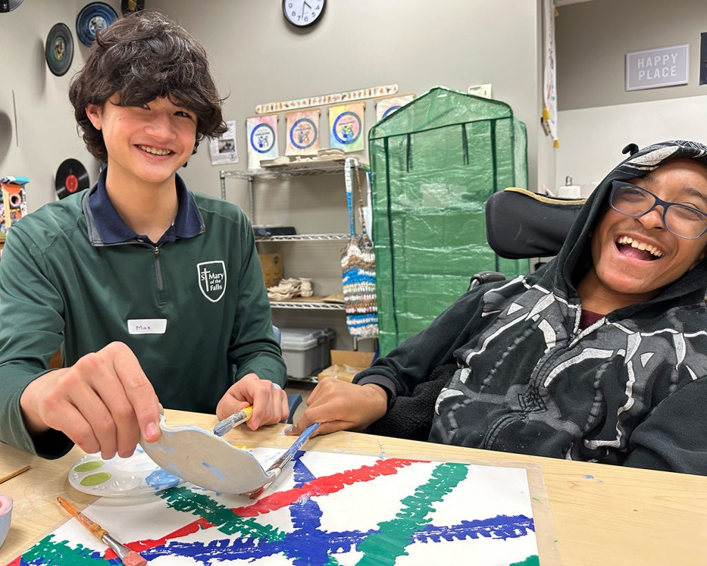 Teens both sitting at a desk doing crafts