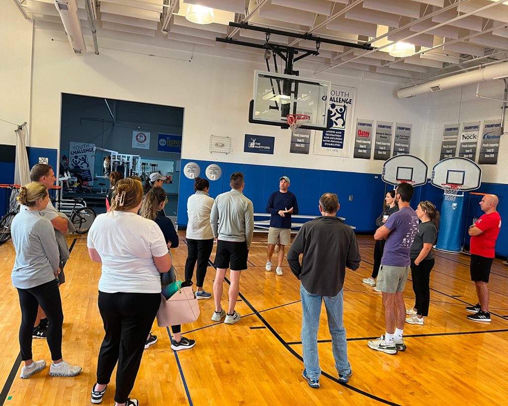 A man speaking in a basketball gym to a group of people