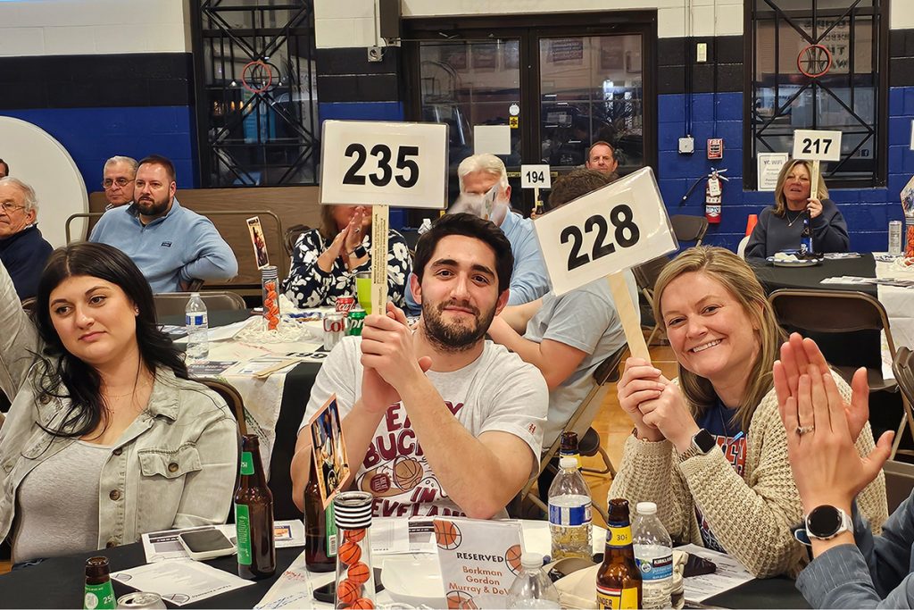 A group of people at an auction, holding their auction signs