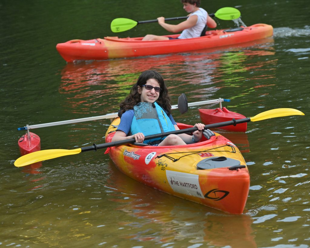 A child sitting in a kayak on a calm lake