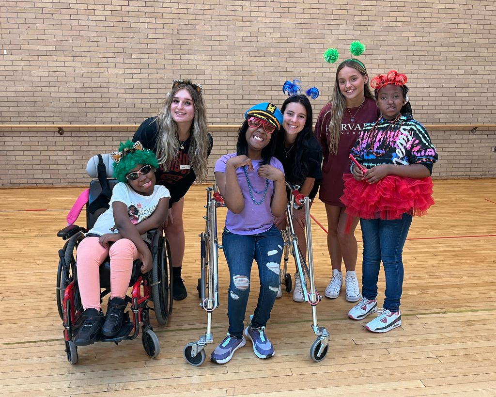 A group of kids, some one in a wheelchair, one using crutches wearing fun clothing