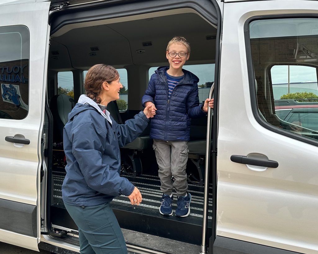 Lady helping kid get out of a van's sliding door
