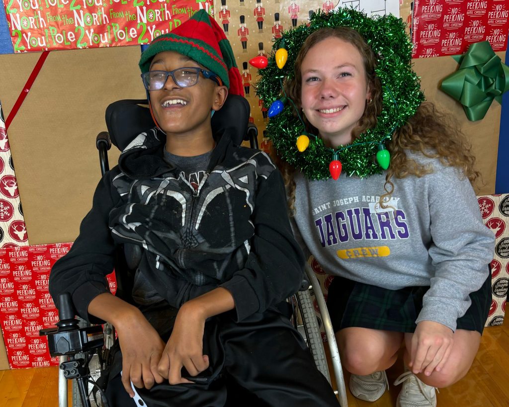 A kid in a wheelchair and another kid wearing christmas clothing