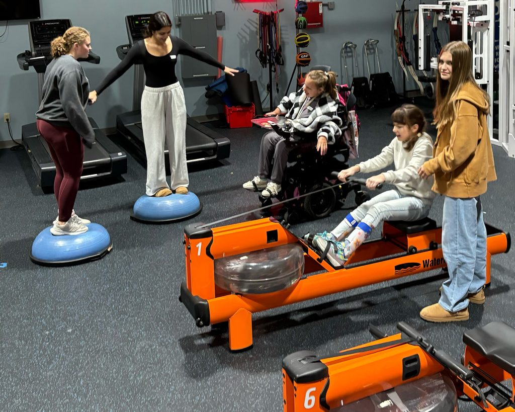Many girls in a gym using gym equipment