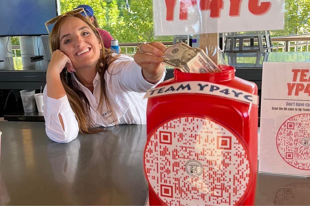 A lady putting money into a red box