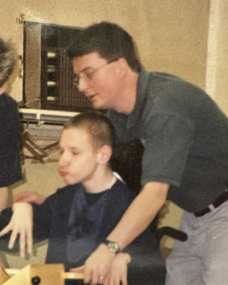 Vintage photo of Ken working with a child sitting in a wheelchair