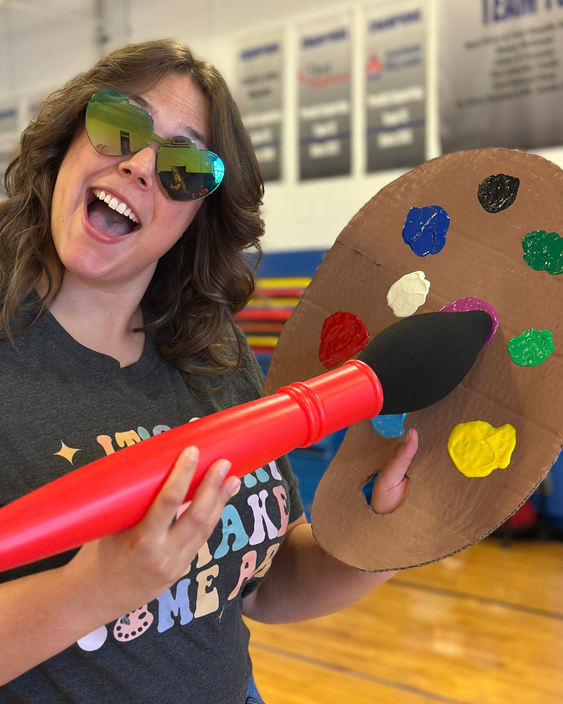 Megan with sunglasses on and a fake artistic brush and pallet