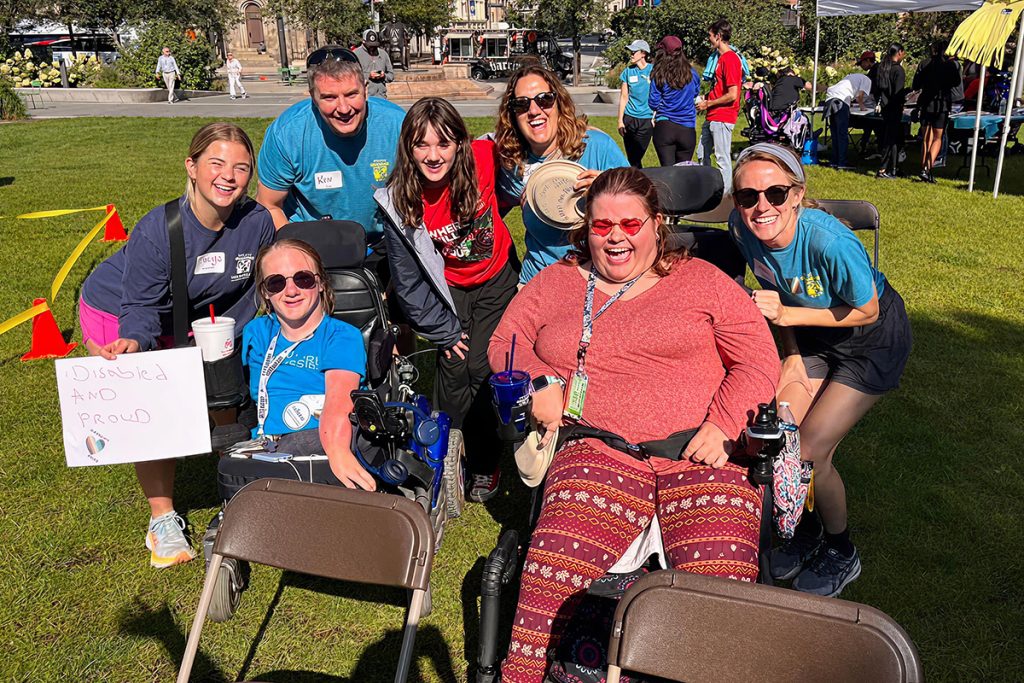 A group of people outside all leaning over to pose for a photo