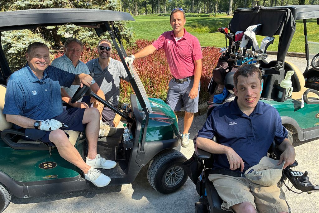 a group of men standing in and by golf carts at a golf course