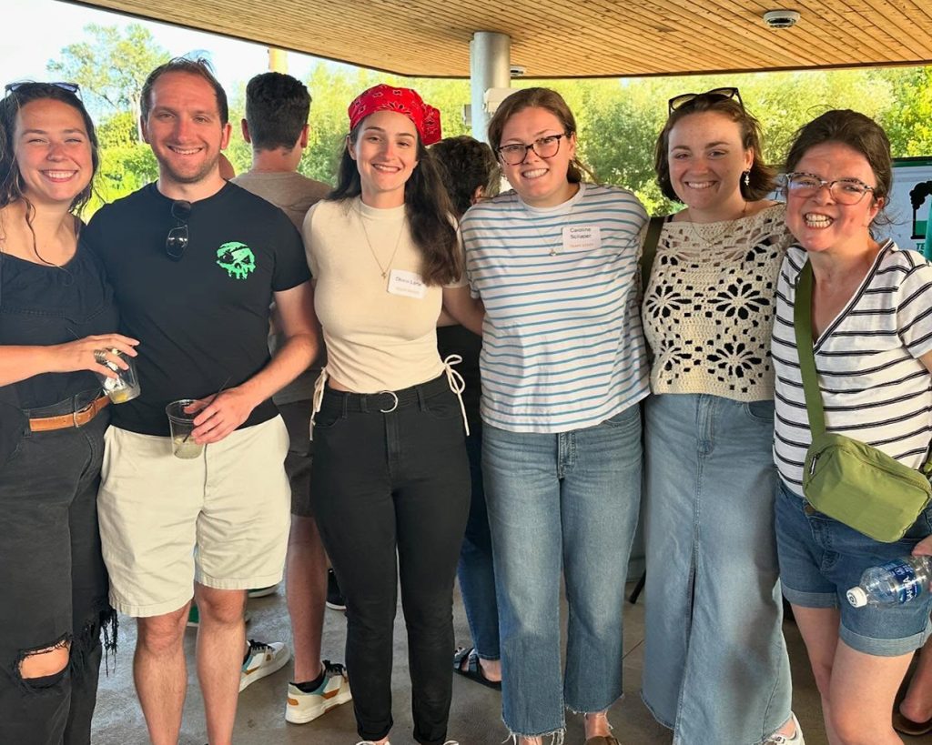 A group of people standing in a covered porch posing for the camera