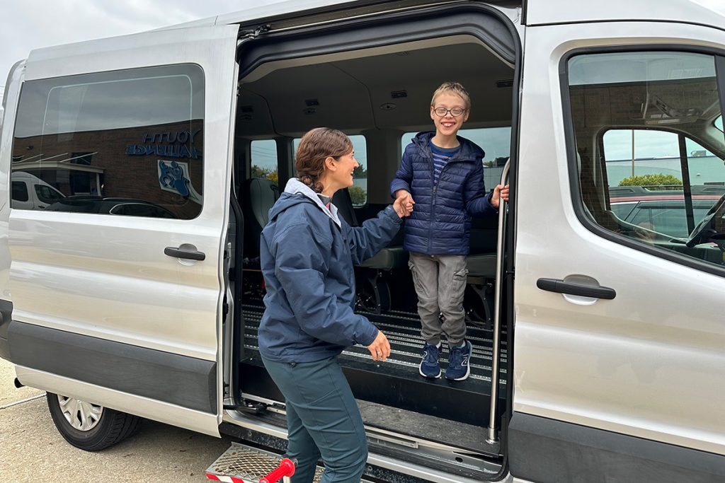 A lady helping a child out of a van