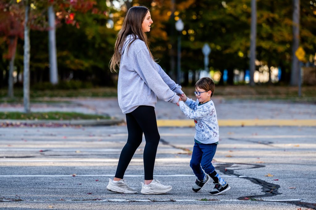 A teen holding a boy with glasses dancing or playing