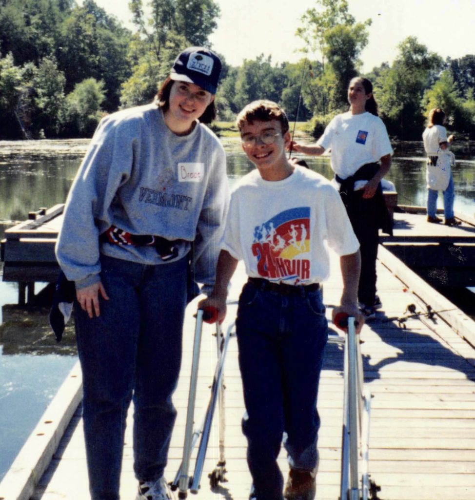 A women stands next to a boy with a walker. They are both smiling.