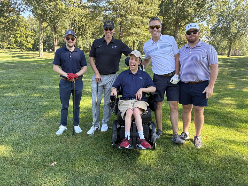 five men stand in the grass smiling