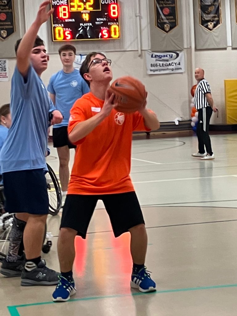 teen boy gets ready to make basket, while another teen boy attempts to block