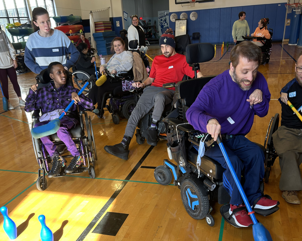 A group of adults play field hockey in a gym