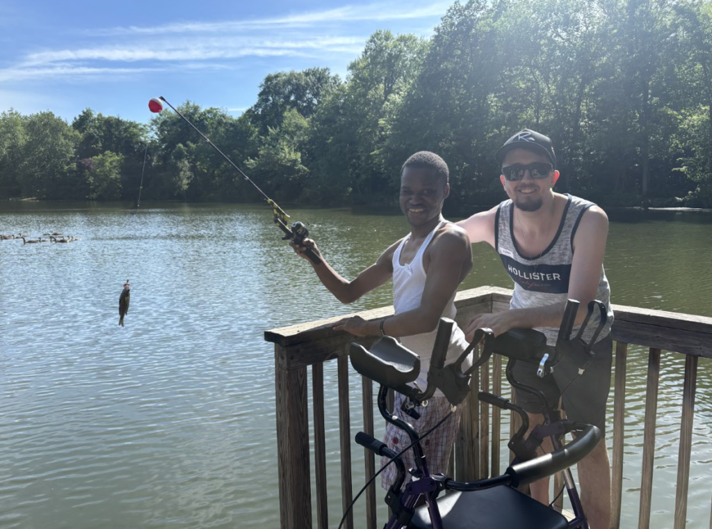 Two young men fish together, one has a walker.