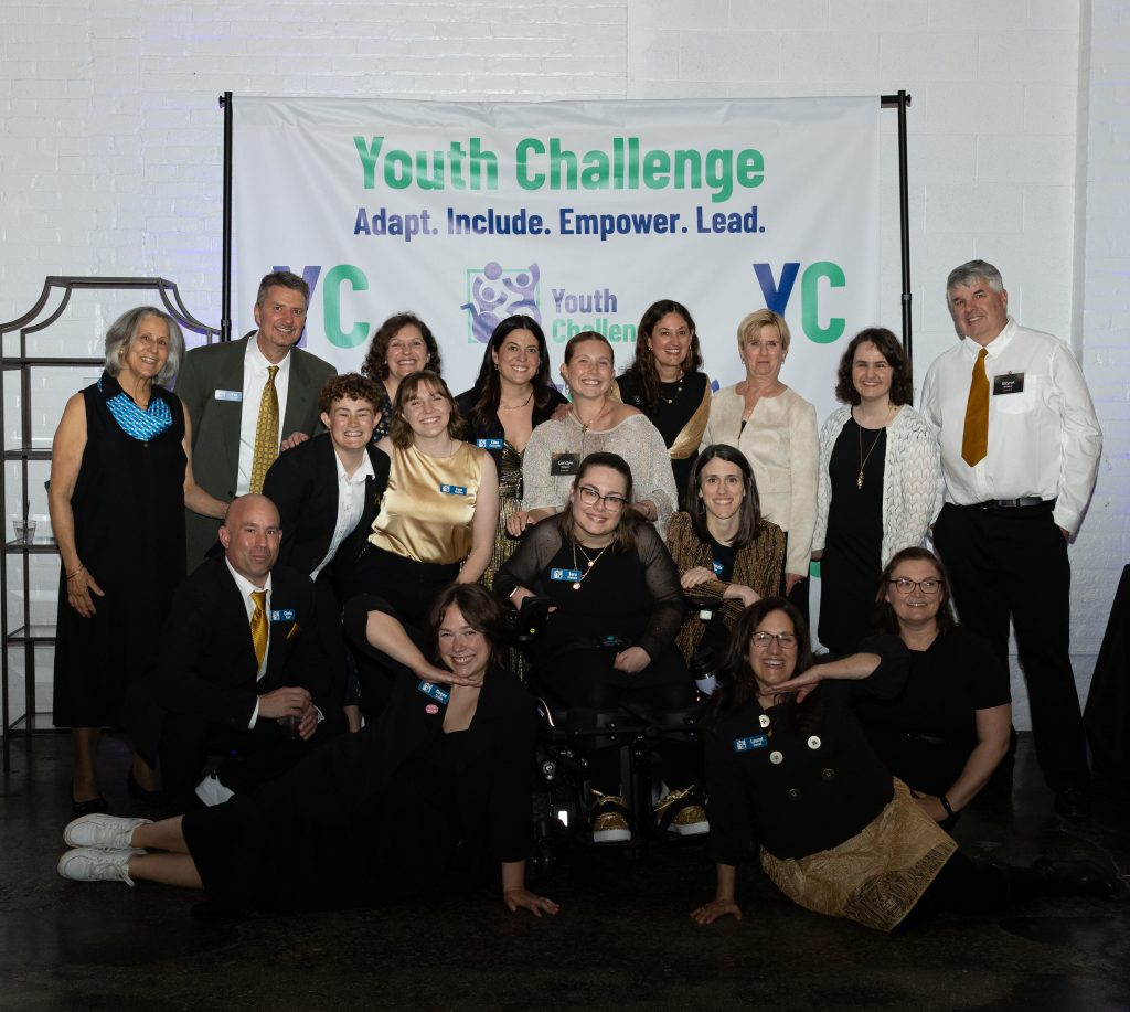 The YC staff smiles in front of a banner