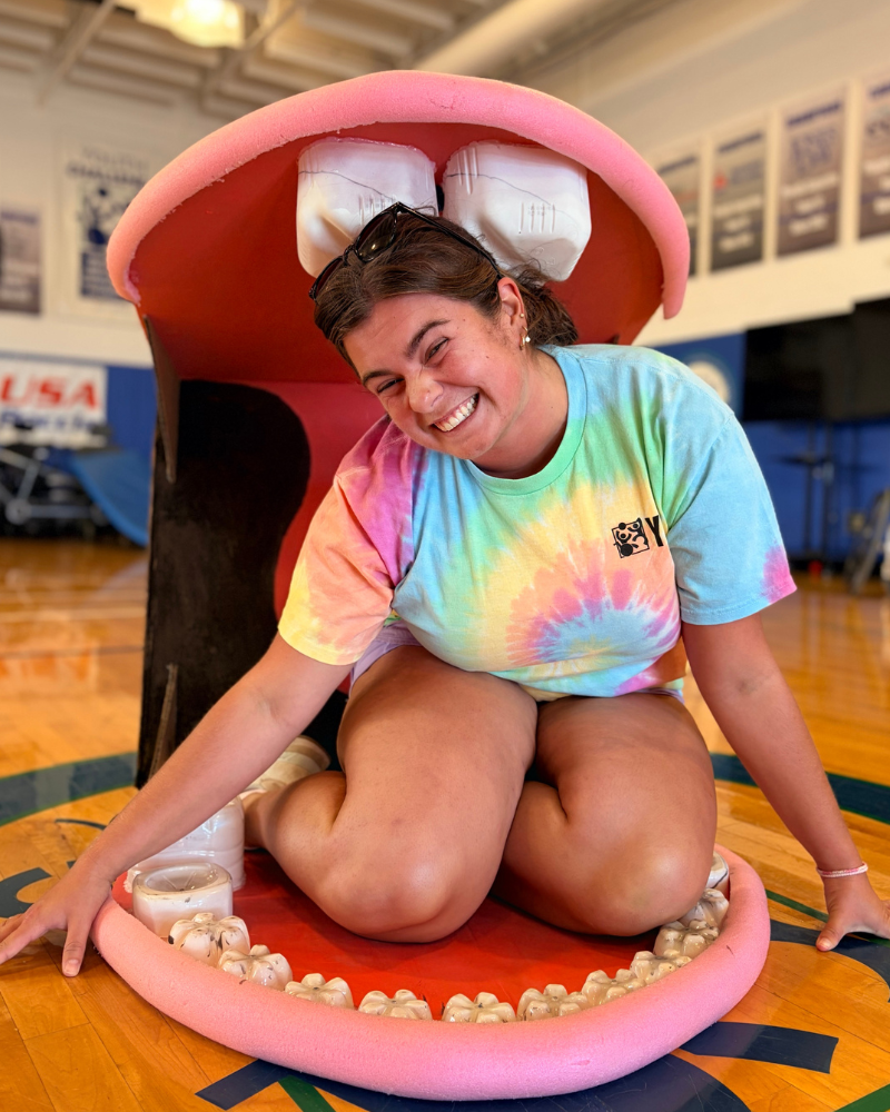 A woman smiles while sitting in a fake mouth.