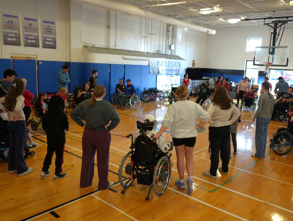 YC Participants and Volunteers getting ready to do their vocal warmups in a big circle with Sarah in the gym.